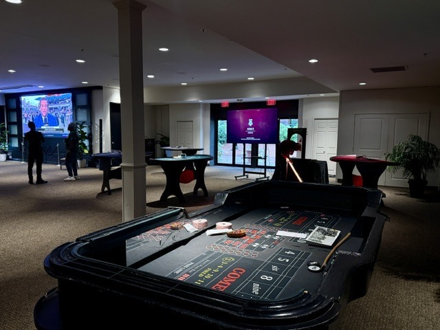 Craps table and cocktail tables in an event space with projection screens