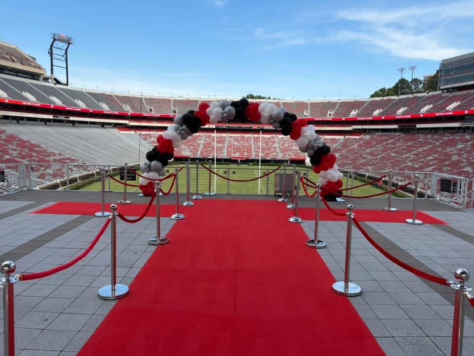 Red carpet entrance and balloon arch overlooking a football stadium